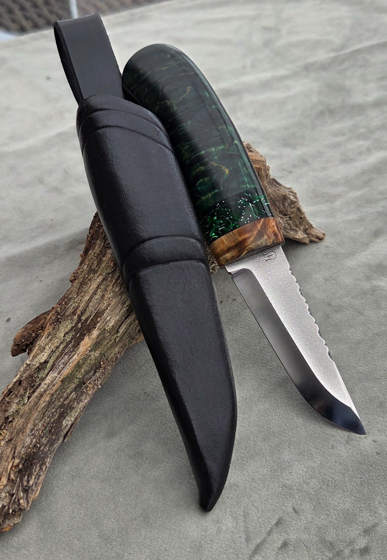 2026 "Glaskogen 5/2026". Rostfritt blad med filework "Ull" av Michael Holmström. Skaft av masurbjörk som färgat med narvsvärta. Front av stabiliserad masurbjörk, detaljer av raffir med silverstripes och vulkanfiber. Knivslida av färgat rårandsläder.